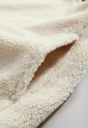 Cremefarbene Fleece-Decke mit einer weichen, strukturierten Oberfläche, die ein leicht plüschiges Gefühl und abgerundete Kanten aufweist.