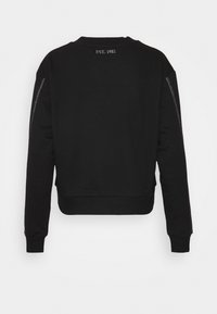 Sudadera negra con un diseño cropped, puños y dobladillo acanalados, y un detalle bordado que dice 'EST. 1981' en la parte posterior. Textura suave, cremalleras laterales.