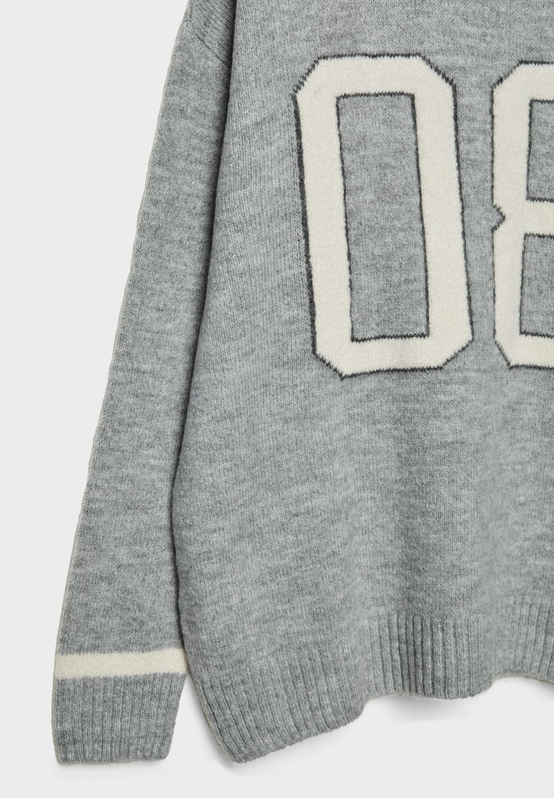 Grauer Pullover mit großem cremefarbenem Design der Nummer "08". Verfügt über einen gerippten Saum und Bündchen, eine weiche Textur und einen kontrastierenden gestreiften Akzent an den Ärmeln.