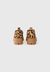 Leopardmønstrede slip-on sko med brune gummisåler, tekstureret stof og en løftestrop bagpå for nem påtagning.