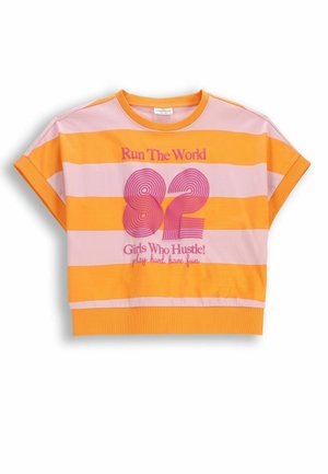 Krótki rękaw, prążkowana koszulka w kolorze pomarańczowym i różowym z napisem „Run The World 82 Girls Who Hustle! play hard, have fun” różowymi literami.