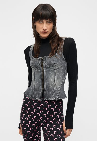Τζιν κορσές σε ξεθωριασμένο μαύρο με διαμορφωμένο μπούστο και κλείσιμο με φερμουάρ. Συνδυάζεται με μαύρα κολάν που έχουν μοτίβο ροζ φεγγαριού σε σχήμα ημισελήνου.