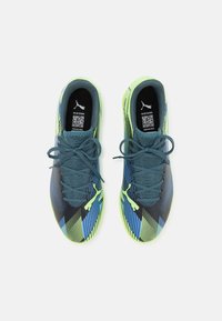 Zapatillas deportivas con un diseño en negro y verde, con rayas diagonales azules, parte superior texturizada y suela verde. Incluye cordones y logo de la marca.