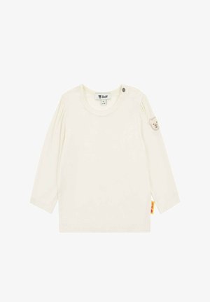 Langärmliges cremefarbenes Hemd aus weicher Baumwolle mit rundem Ausschnitt, Knopfdetail an der Schulter und einem Bären-aufnäher am Ärmel.