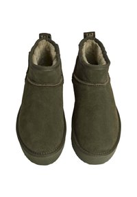 Botas de tobillo de ante verde oliva con forro de piel suave, caña baja, punta redonda y costuras decorativas. Incluye una tira de tela en el talón.