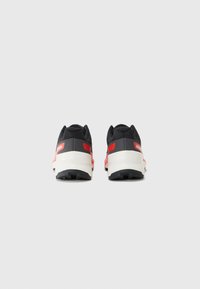 Black athletic shoes with red accents, textured fabric upper, lightweight contrasting white midsole, and rubberized black outsole.
