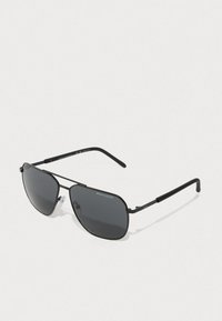 Zwarte metalen zonnebril met donkere lenzen, aviatorvorm, dunne pootjes en verstelbare neuspads, met 'Armani Exchange' branding.