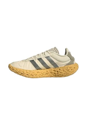 Sneaker bianco con strisce grigie e suola spessa texturizzata color marrone chiaro, vista laterale, senza sfondo.