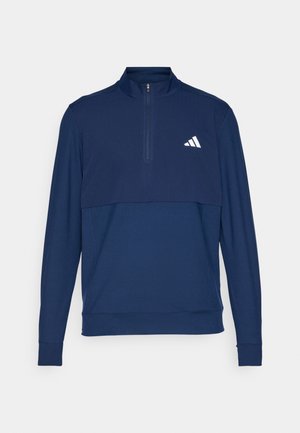 Navy blue pullover with a zippered neck, made of soft fabric. Features tonal upper panel and white logo on the left chest. Long sleeves and cuffs.