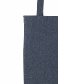 Sac fourre-tout en tissu texturé bleu foncé avec une seule sangle de poignée visible sur un fond blanc.