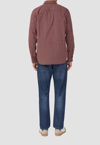 Karierte braun-rote Langarmbluse mit abgerundetem Saum, getragen zu blauen Denim-Jeans und weißen Turnschuhen, zeigt eine lässige Rückansicht.