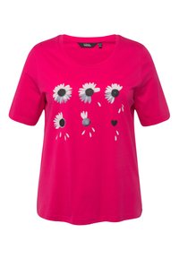 Camiseta de algodón rosa con un diseño floral que presenta margaritas blancas, centros negros y pequeños acentos en forma de corazón, mangas cortas y un cuello redondo.