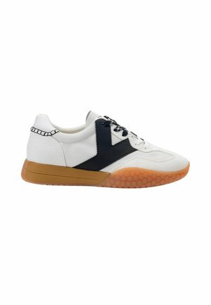 Sneaker bianca con motivo chevron nero, lacci bianchi e neri e suola marrone testurizzata con motivo a nido d'ape nella metà anteriore.