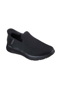Zapato negro tipo slip-on elaborado con tejido texturizado, que cuenta con una suela acolchada con agarre estampado y un logotipo sutil en el lateral.