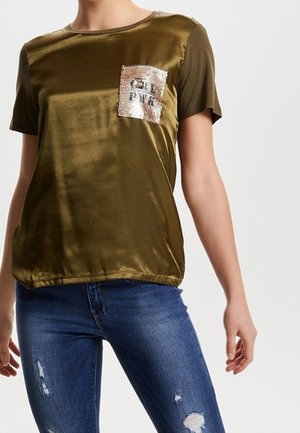 Olivengroene satijnen T-shirt met korte mouwen, ronde hals en een pailletten zak met een tekstontwerp. Spijkerbroek met versleten details.