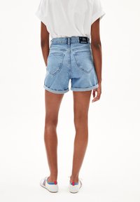 Shorts de mezclilla con cintura alta, dobladillos enrollados y un lavado claro. Cuenta con dos bolsillos traseros y una etiqueta negra en la cinturilla.