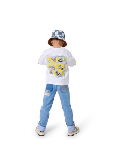 Witte T-shirt met een kleurrijke afbeelding op de achterkant, gecombineerd met lichtblauwe spijkerbroek. Het kind draagt een blauw-wit geruit vissershoedje.