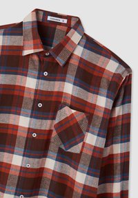 Camicia in flanella a quadri rossi, blu e crema con collo, bottoni bianchi e tasca sul petto. Tessuto morbido con una vestibilità standard.