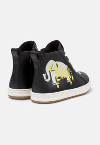 Svart høye sneakers med hvite såler, hvite lisser og et gult og hvitt abstrakt elefantgrafikk på yttersiden.