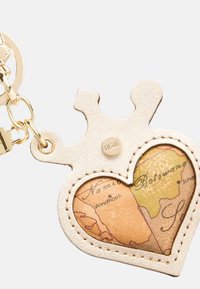 Portachiavi a forma di cuore in pelle crema con un design mappa all'interno, caratterizzato da una parte superiore a forma di corona e dettagli in hardware dorato.