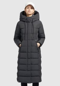 Lunga giacca a vento nera con cappuccio, caratterizzata da un motivo trapuntato, cordoncino e tasche laterali con zip. Tessuto liscio e resistente all'acqua.