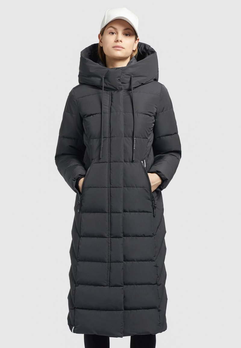 Lunga giacca a vento nera con cappuccio, caratterizzata da un motivo trapuntato, cordoncino e tasche laterali con zip. Tessuto liscio e resistente all'acqua.