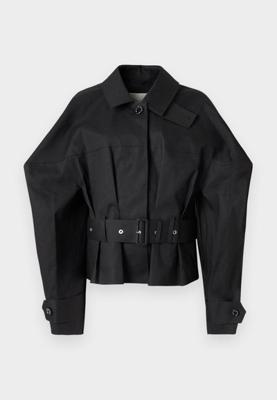 Giacca nera corta con un design strutturato, colletto ampio, chiusura con un singolo bottone e una cintura larga con accessori metallici.