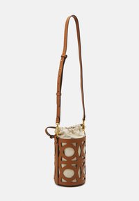 Brown leather bucket bag with cut-out geometric patterns, cream drawstring fabric interior, adjustable strap, and gold hardware accents.