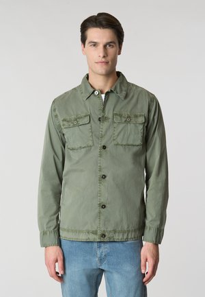 Giacca leggera verde in tessuto, caratterizzata da una chiusura frontale con bottoni, due tasche sul petto e polsini regolabili. Design semplice con vestibilità casual.