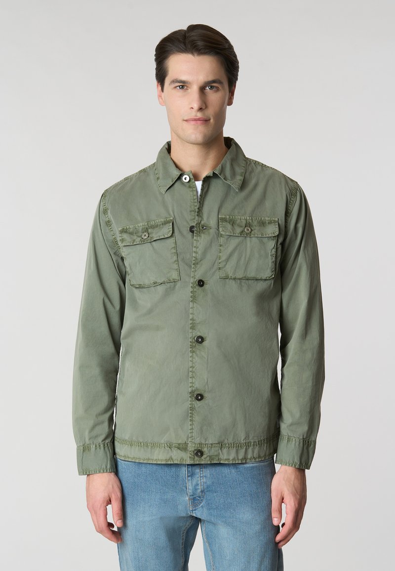 Giacca leggera verde in tessuto, caratterizzata da una chiusura frontale con bottoni, due tasche sul petto e polsini regolabili. Design semplice con vestibilità casual.