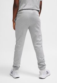 Graue Jogginghosen mit schmalem Schnitt und elastischem Bund. Der Stoff sieht weich mit einer glatten Textur aus und wird mit weißen Sportschuhen kombiniert.
