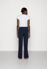 Navy, wide-leg trousers with an elastic waistband, paired with a fitted white T-shirt. Smooth fabric, relaxed fit, minimalistic design.
