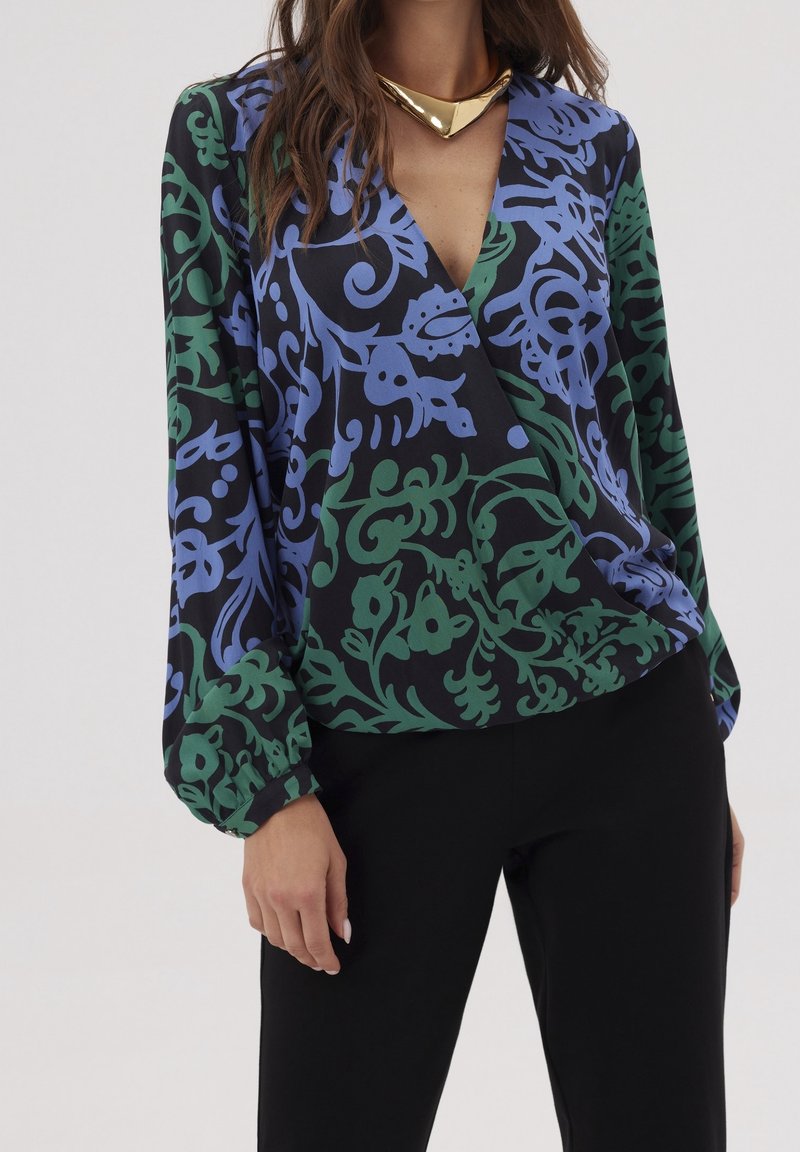 Blouse à manches longues en tissu noir avec un motif floral abstrait vert et bleu, dotée d'un profond décolleté en V et d'un fit décontracté.