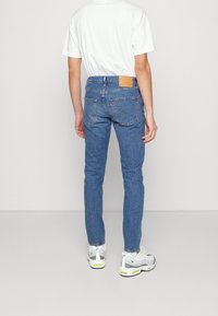 Skinny blue jeans with a classic five-pocket design, made of denim. Features a leather logo patch on the back waist and subtle stitching details.
