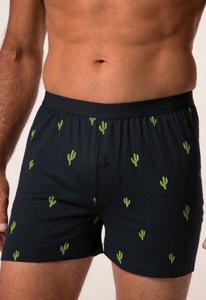 Cajones de algodón negros con pequeños patrones de cactus verdes, con botón en la parte delantera y cintura elástica con un logo.