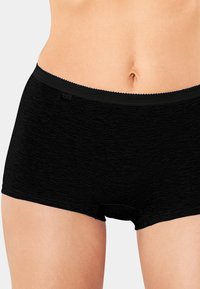 Svarta boyshort-underkläder med en slät yta och spetsdetalj på midjebandet. Tillverkade av mjukt, stretchigt material för komfort.