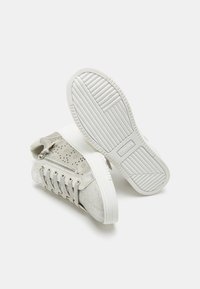 Light grey sneakers with textured surfaces, perforated accents, white rubber soles, and a side zipper detail. Minimalistic design.