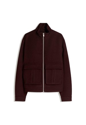 Veste marron foncé zippée avec col montant et deux grandes poches à rabat devant sur fond blanc.