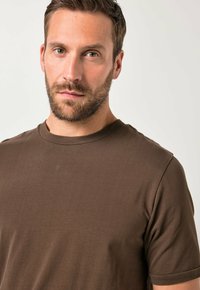 Hnědé tričko s krátkým rukávem z jemné bavlněné látky, s kulatým výstřihem a hladkou strukturou bez vzorů či ozdob.