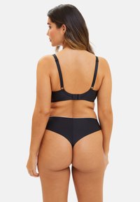 Ensemble de bikini noir avec une texture lisse, des bretelles réglables et une fermeture à crochet dans le dos. Bas taille haute avec une couverture minimale.