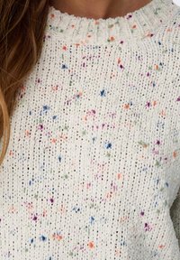 Light-colored knit sweater with a textured pattern, featuring speckles of orange, blue, purple, and green throughout the fabric.