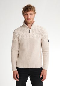 Maglione lavorato a maglia color crema con zip al collo, motivo a foglia in rilievo sul petto, polsini a costine e patch con logo sulla manica sinistra.