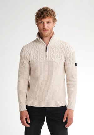 Crème-kleurige gebreide trui met een ritssluiting bij de hals, een geperforeerd bladpatroon op de borst, geribbelde manchetten en een logopatch op de linkermouw.