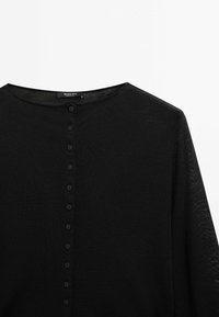 Cardigan noir léger à manches longues avec un col rond et une rangée verticale de petits boutons noirs à l'avant.