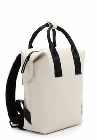 Wasserfester Rucksack aus glattem Material in Cremefarbe, mit schwarzen verstellbaren Tragegurten, einem oberen Griff, einer seitlichen Reißverschlusstasche und minimalistischem Design.