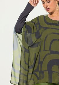 Fløjlsagtig tunika med et grønt og gråt abstrakt mønster, lavet af et let, gennemsigtigt stof og med et langærmet gråt underlag.