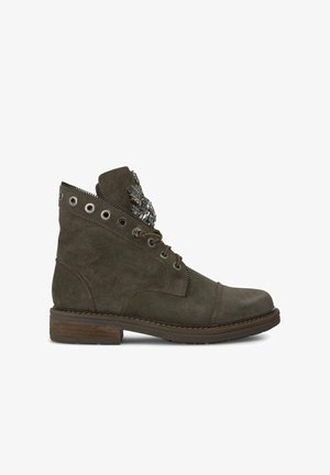 Bottines en suede vertes avec un col incurvé, des œillets en métal et des accents décoratifs. Elles possèdent un petit talon carré et des détails de couture.