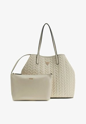 Sac à main matelassé beige avec longues poignées et pochette assortie beige avec fermeture éclair, tous deux ornés des logos de la marque Guess.