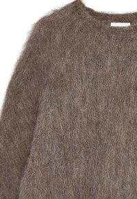 Brązowy, puszysty sweter z okrągłym dekoltem. Wykonany z miękkiej, teksturowanej tkaniny, ma luźny krój i minimalistyczny design.