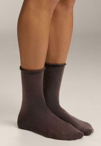 Braune Baumwollsocken mit weicher Textur, mittlerer Wadenlänge und gerippten Bündchen. Glatte Oberfläche mit minimalen Nahtdetails.